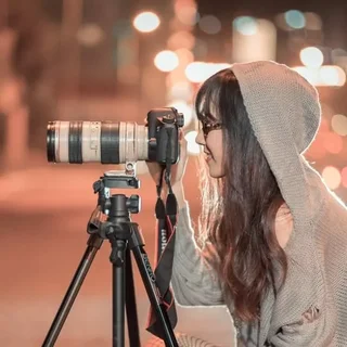 Une photographe avec un appareil professionnel sur un trépied en pleine nuit lumineuse